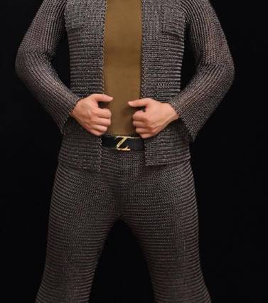 A person is wearing a suit of dark brown chainmail shirt and chainmail chausses.