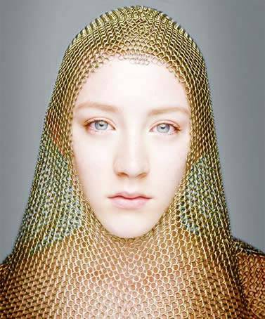 A woman is wearing a golden color chainmail coif.