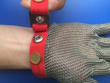 A hand is holding an end of red strap of the chainmail glove on the blue board.