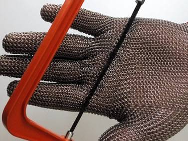 A hand wearing a piece of chainmail glove is sawing by a saw.