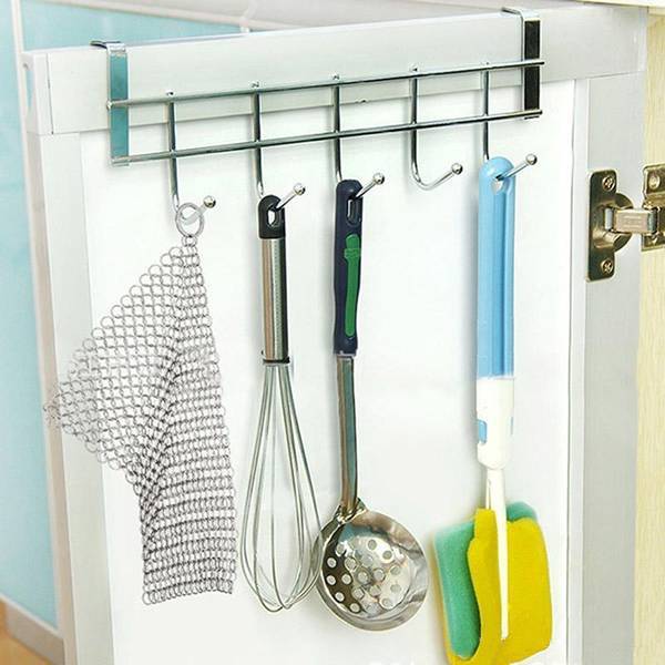 There is a stainless steel scrubber, a whisk, a bamboo and a pan brush on the shelf.