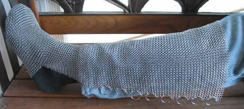 The silver white chainmail chausses is covering part of leg and foot.